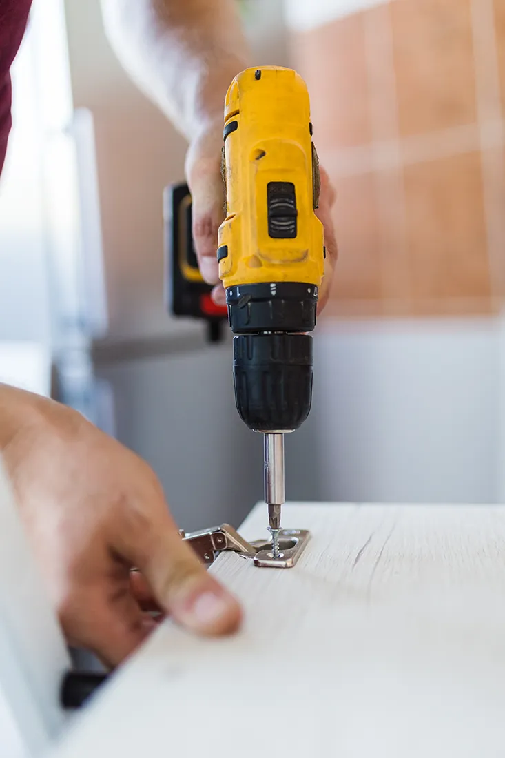 Operatore monta mobile per cucina con trapano giallo